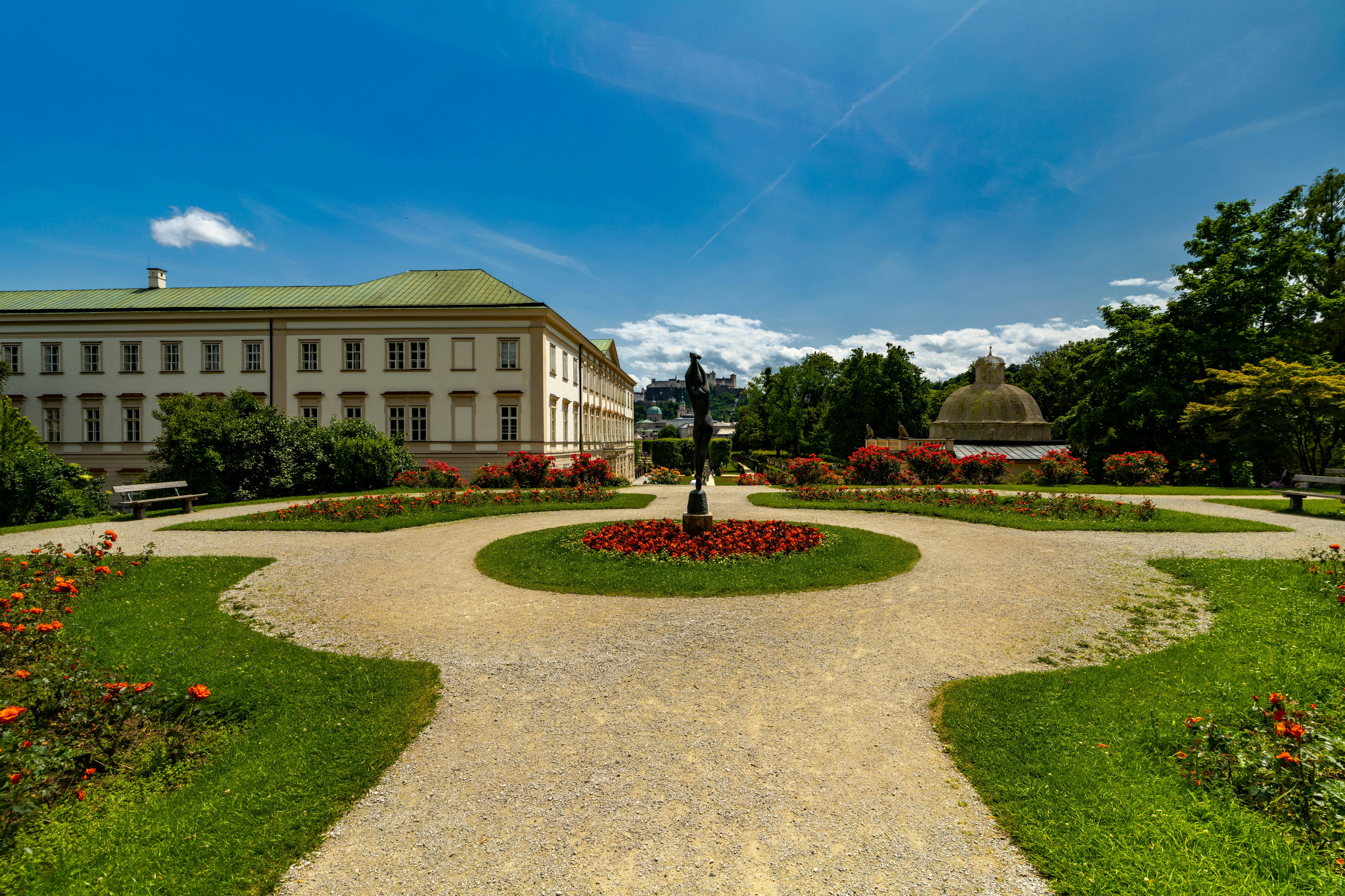 גן רשמי עם פסל ומבנה היסטורי | Formal Garden with Statue and Historical Building