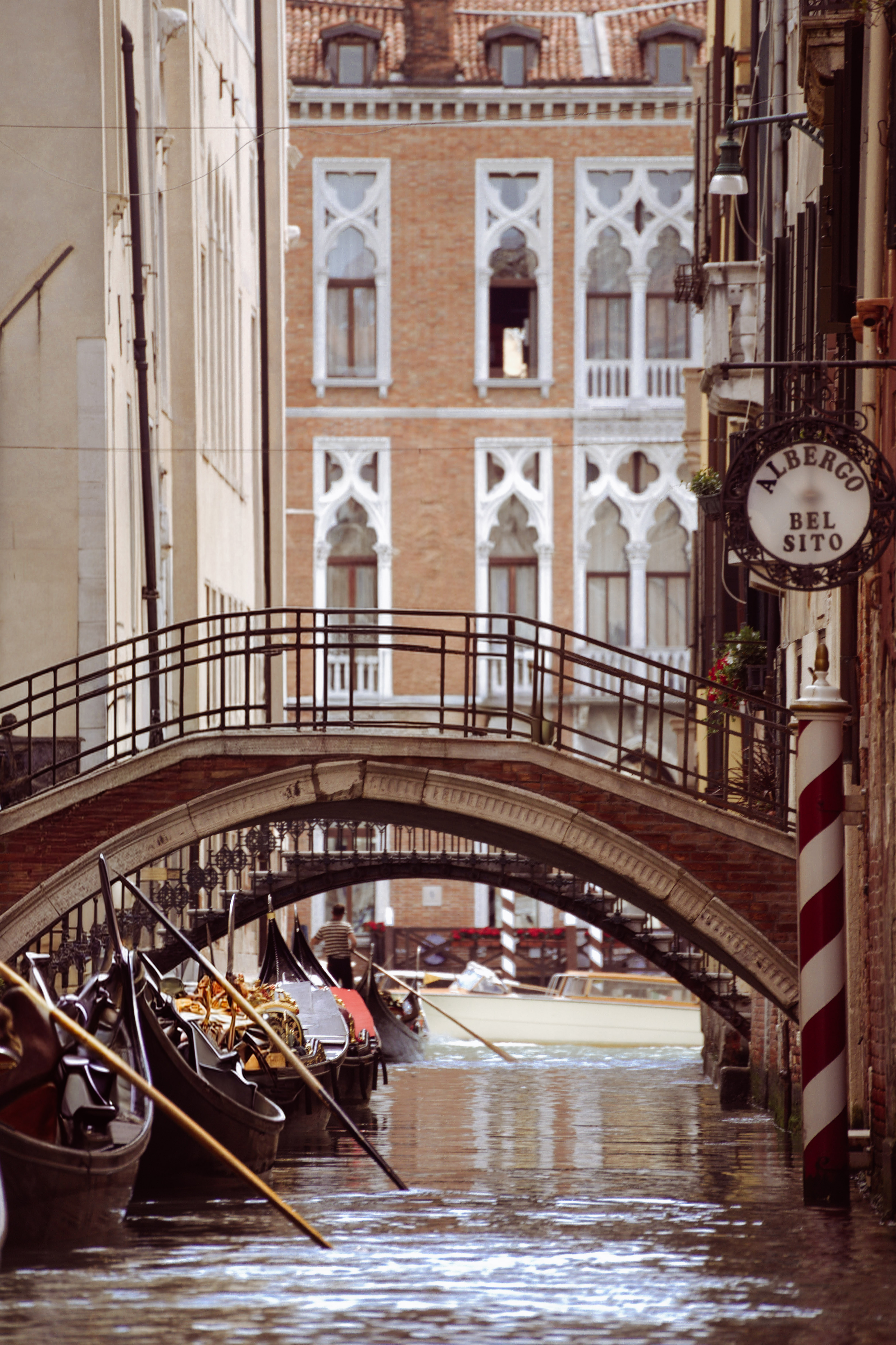 גונדולות עוגנות בתעלה צרה תחת גשר אבן בוונציה