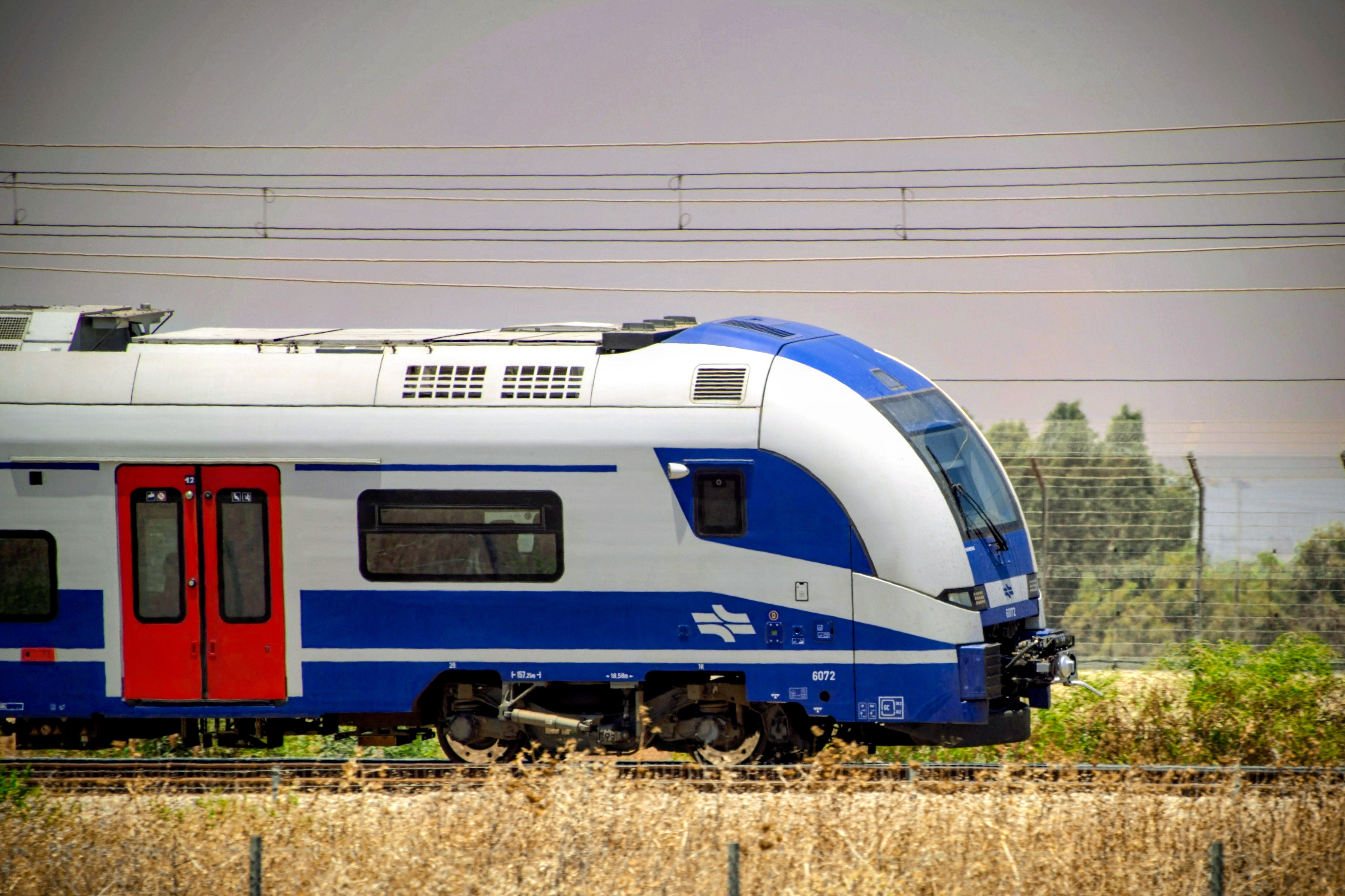 רכבת נוסעים חשמלית של רכבת ישראל נוסעת על מסילה בנוף פתוח